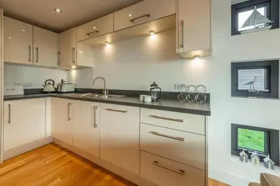 a kitchen with white cabinets and black counter tops at Morvah in St. Agnes