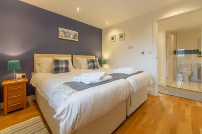 a bedroom with a large bed and a bathroom at Morvah in St. Agnes