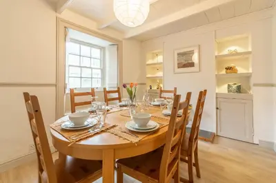 a dining room with a wooden table and chairs at Porthgwidden Cottage in Uny Lelant