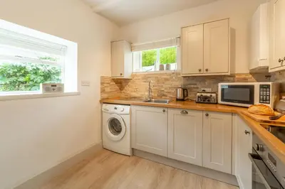 a kitchen with a washing machine and a microwave at Porthgwidden Cottage in Uny Lelant
