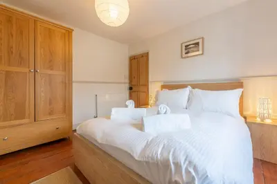 a bedroom with a large bed with white sheets at Porthgwidden Cottage in Uny Lelant