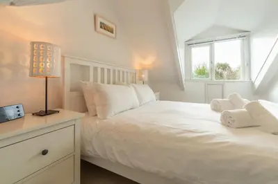 a white bedroom with a bed and a window at Porthgwidden Cottage in Uny Lelant