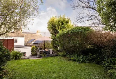 a garden with a table and an umbrella at Porthgwidden Cottage in Uny Lelant