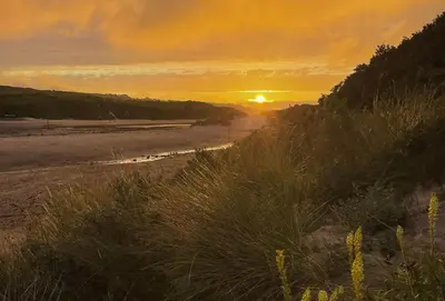 a sunset on the beach with the sun setting at Porthgwidden Cottage in Uny Lelant