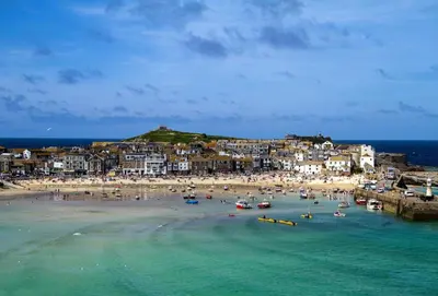 a beach with a bunch of boats in the water at Porthgwidden Cottage in Uny Lelant
