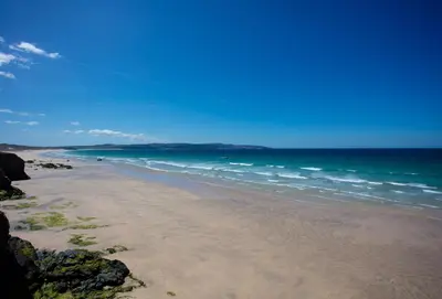 a sandy beach with the ocean in the background at Porthia in Hayle