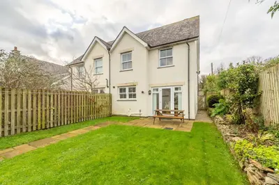 a white house with a fence and a yard at Porthia in Hayle