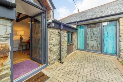 a stone house with glass doors and a patio at Potter's Barn in St. Agnes
