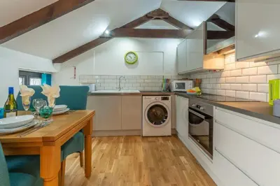 a kitchen with a table and a washing machine at Potter's Barn in St. Agnes