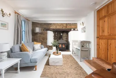a living room with a blue couch and a fireplace at Roseneath in St. Agnes