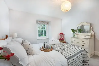 a bedroom with a bed with a mirror and a dresser at Roseneath in St. Agnes