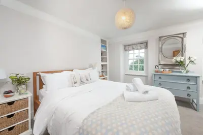 a white bedroom with a large bed and a mirror at Roseneath in St. Agnes