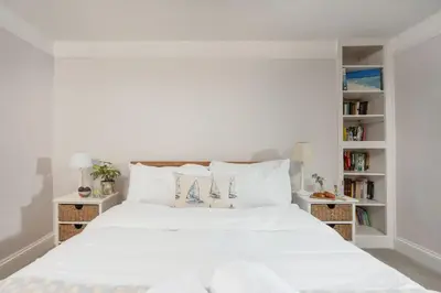 a bedroom with a white bed and bookshelves at Roseneath in St. Agnes