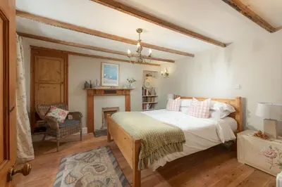 a bedroom with a large bed and a chair at Roseneath in St. Agnes