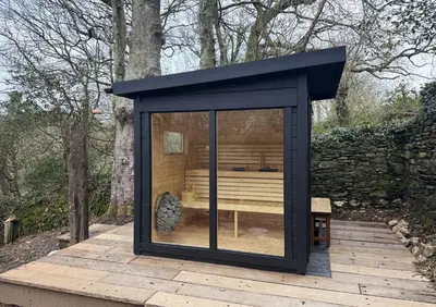 a large black shed on a wooden deck at Rose in Vale Cottage in Perranzabuloe