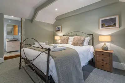 a bedroom with a bed and a sink in it at Rose in Vale Cottage in Perranzabuloe