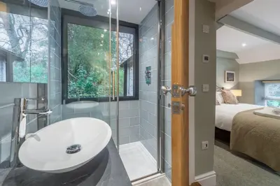 a bathroom with a sink and a glass shower at Rose in Vale Cottage in Perranzabuloe