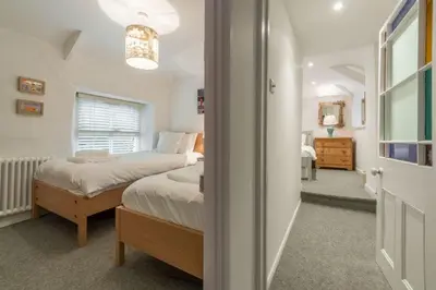 a bedroom with a bed and a room with a window at Rose in Vale Cottage in Perranzabuloe