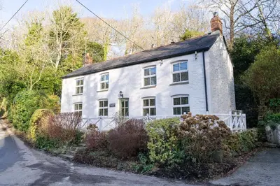a white house with a chimney on top of it at Rose in Vale Cottage in Perranzabuloe