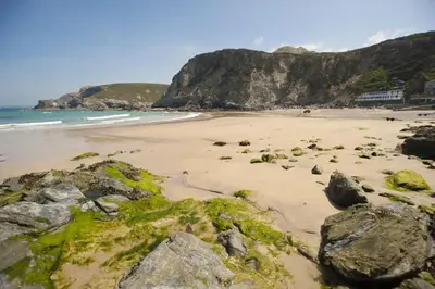 a beach with rocks and the ocean and a mountain at Rose in Vale Cottage in Perranzabuloe