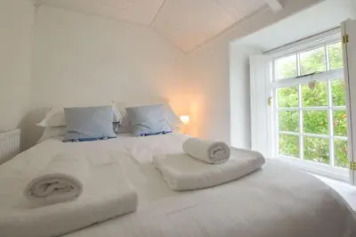 a white bedroom with a large white bed with pillows at Scrumbles Hollow in St. Agnes