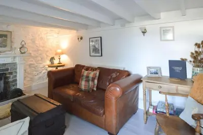 a living room with a leather couch and a fireplace at Scrumbles Hollow in St. Agnes