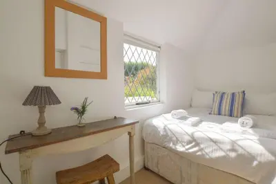 a bedroom with a bed and a mirror and a window at Scrumbles Hollow in St. Agnes