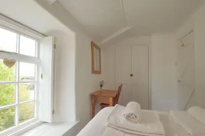a white bedroom with a bed and a window at Scrumbles Hollow in St. Agnes