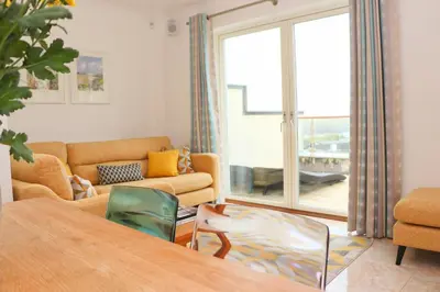 a living room with a couch and a table at Beachside apartment, sea views in St Merryn