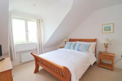 a bedroom with a large bed and a window at Beachside apartment, sea views in St Merryn