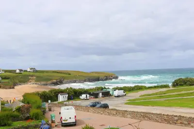 a group of vehicles parked next to the ocean at Beachside apartment, sea views in St Merryn