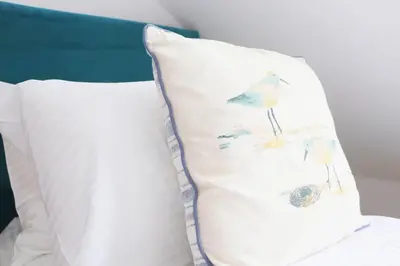 a pillow with a bird on it sitting on a bed at Beachside apartment, sea views in St Merryn