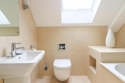 a bathroom with a toilet and a sink and a skylight at Beachside apartment, sea views in St Merryn