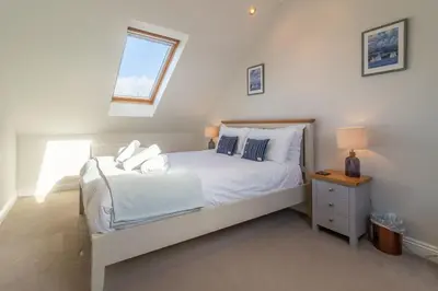 a bedroom with a white bed and a window at Sea Folly in Perranporth