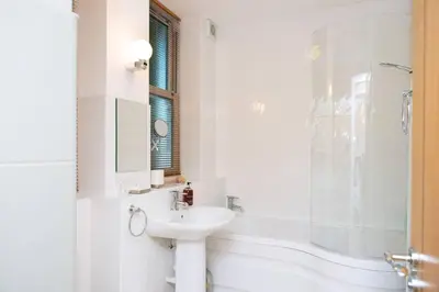 a white bathroom with a sink and a shower at Millendreath at Westcliff - Self Catering flat with amazing sea views in Looe
