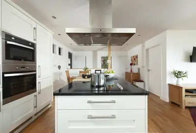 a kitchen with white cabinets and a black counter top at Sea Gem in St. Agnes