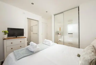 a white bedroom with a bed and a tv at Sea Gem in St. Agnes