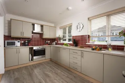 a kitchen with white cabinets and red tiles at September Sea in Port Isaac