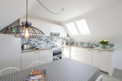 a kitchen with white cabinets and a table at Sunfish in Porthtowan