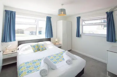 a bedroom with a bed with blue curtains at Sunfish in Porthtowan
