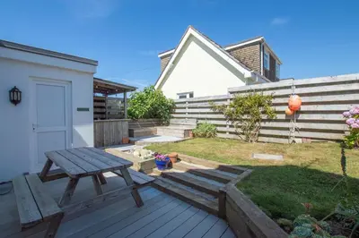 a wooden deck with a picnic table in the yard at Sunfish in Porthtowan