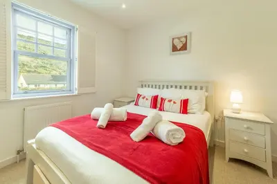 a bedroom with a red and white bed with towels on it at Spring Tide in Porthtowan