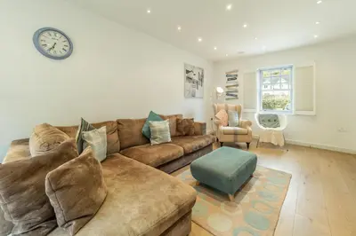a living room with a couch and a clock on the wall at Spring Tide in Porthtowan