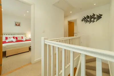 a white room with a bed and a staircase at Spring Tide in Porthtowan