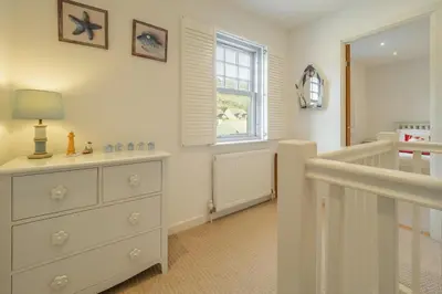 a bedroom with a dresser and a window at Spring Tide in Porthtowan