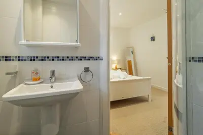 a white bathroom with a sink and a mirror at Spring Tide in Porthtowan