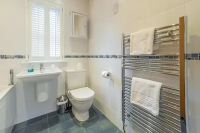 a white bathroom with a toilet and a sink at Spring Tide in Porthtowan