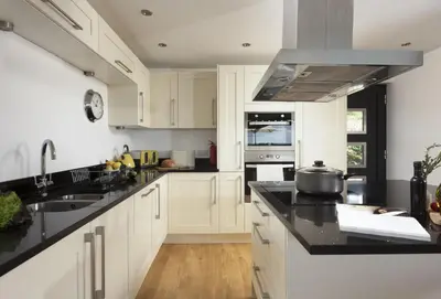 a kitchen with white cabinets and black counter tops at Stargazy in St. Agnes