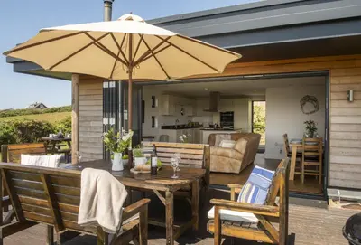 a patio with a wooden table with an umbrella at Stargazy in St. Agnes