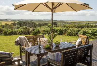 a wooden table with an umbrella on a deck at Stargazy in St. Agnes
